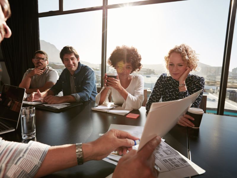 persone in ufficio, un uomo sta facendo vedere dei fogli